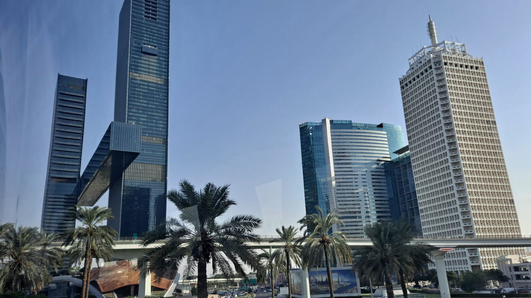Towers along Sheikh Zayed Road in Dubai, seen from street level behind a line of palms
